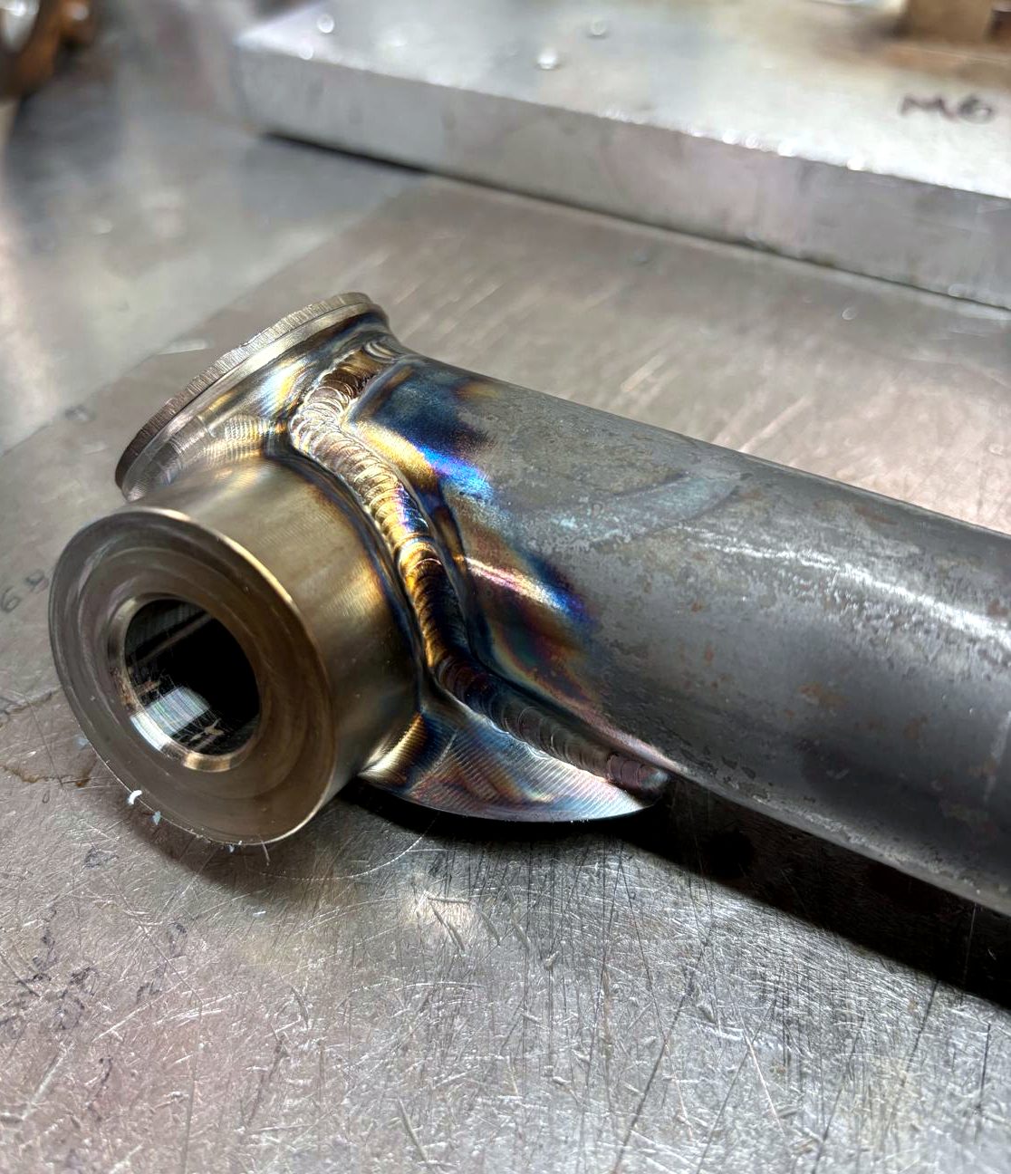 A welded boss on a tube with heat-tinted TIG weld, showing Redwells Engineering's craftsmanship