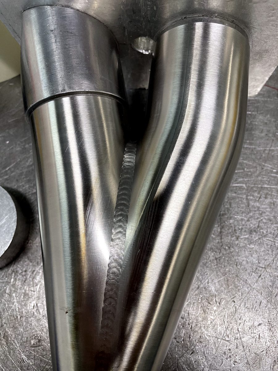 Polished stainless Y-pipe merge with a TIG weld seam